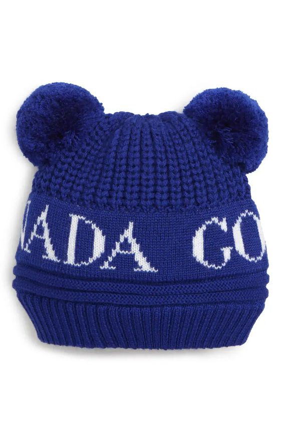 Canada Goose Double Pompom Hat
Blue Knit Hat with Double with Canada Goose Across The Front  & Written With White Capitalize Letters